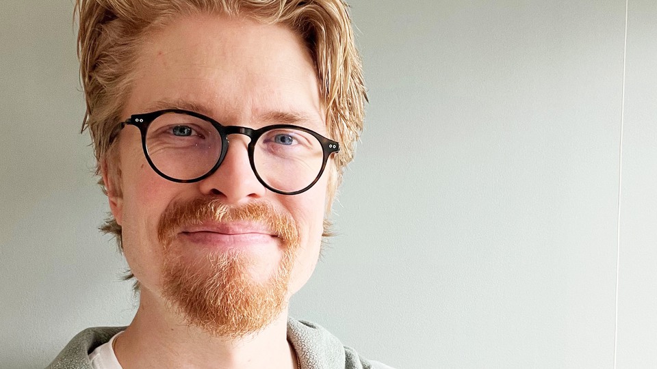 Porträtt av en man med ljust hår, skägg och glasögon