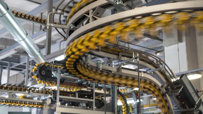 Blurred motion of empty conveyor belts for newspapers and magazines in large modern printing press.
