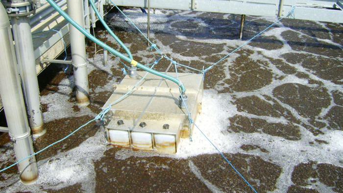 Ett mätinstrument med slangar ligger vatten på en avloppsanläggning, hålls fast med snören.