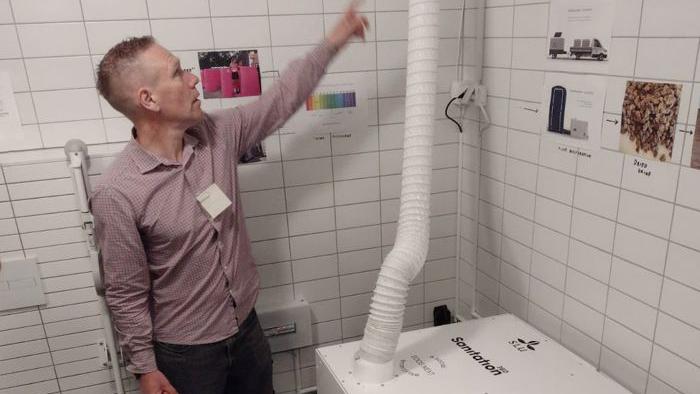 En man pekar på ett rör på en toalett