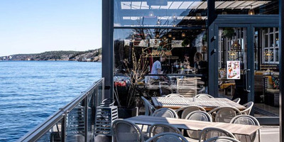 Tables and chairs on a deck overlooking a body of water.